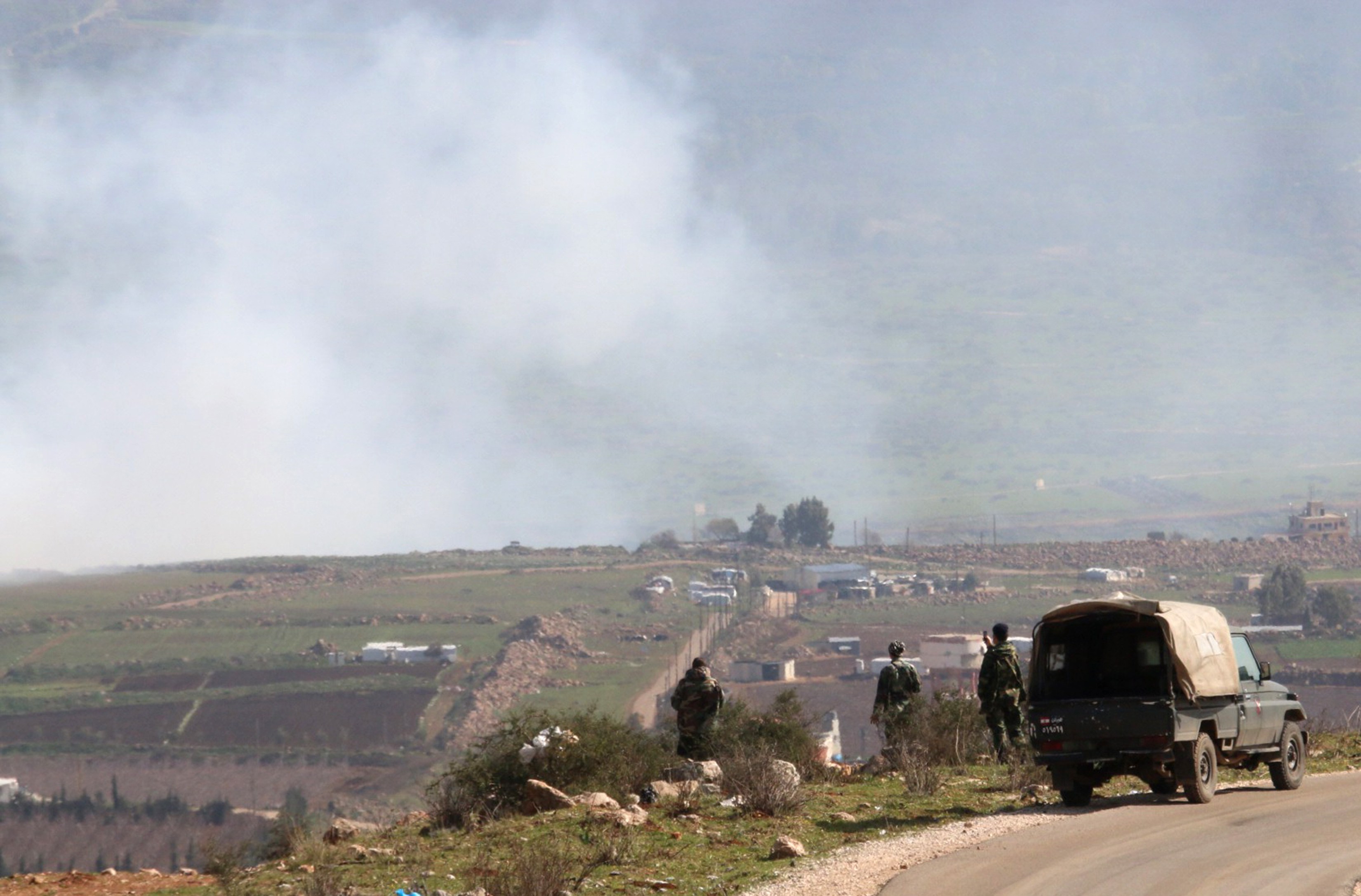 Lebanese army soldiers watch as smoke rises from shells fired from Israel over al-Wazzani area in southern Lebanon
